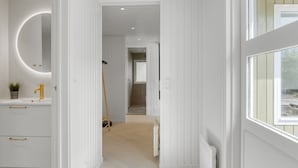 A modern bathroom with a white vanity, a round mirror, and a gold faucet.