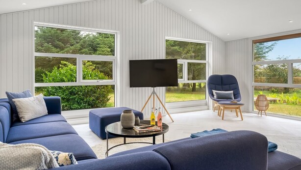A modern living room with a blue sofa, a coffee table, and a flat-screen TV on a tripod stand.