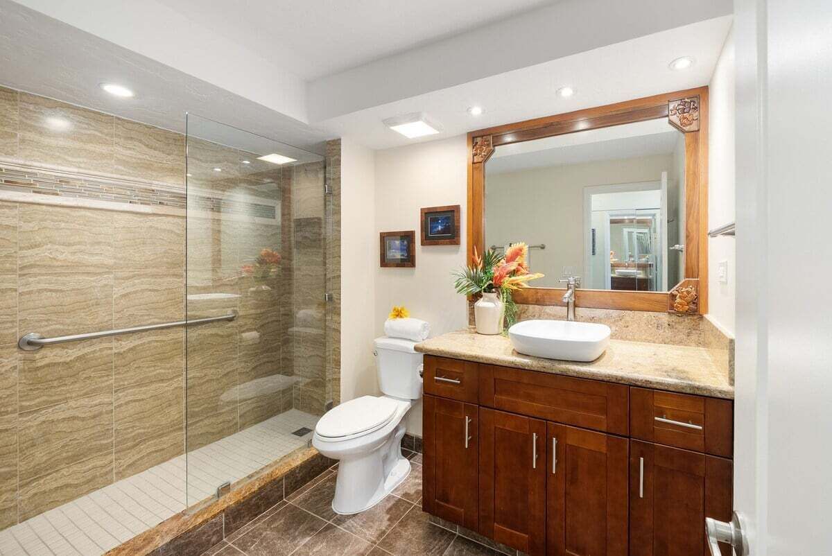 Ein modernes Badezimmer mit Duschkabine aus Glas, einer weißen Toilette und Holzschränken.