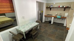 Un espacio habitable compacto con comedor, kitchenette y una cama.