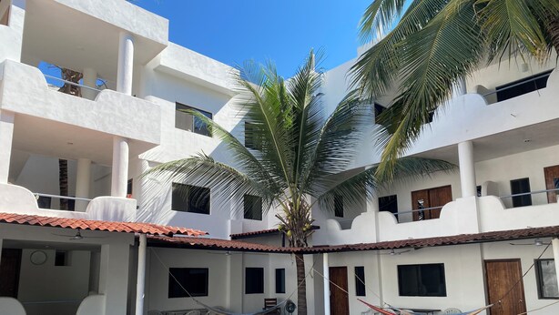 Un patio con edificios blancos, palmeras y mobiliario para exterior.