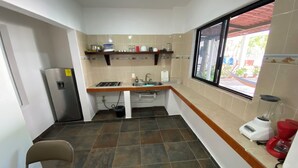 Una cocina compacta con estufa a gas, lavamanos y ventana con vistas a un jardín.