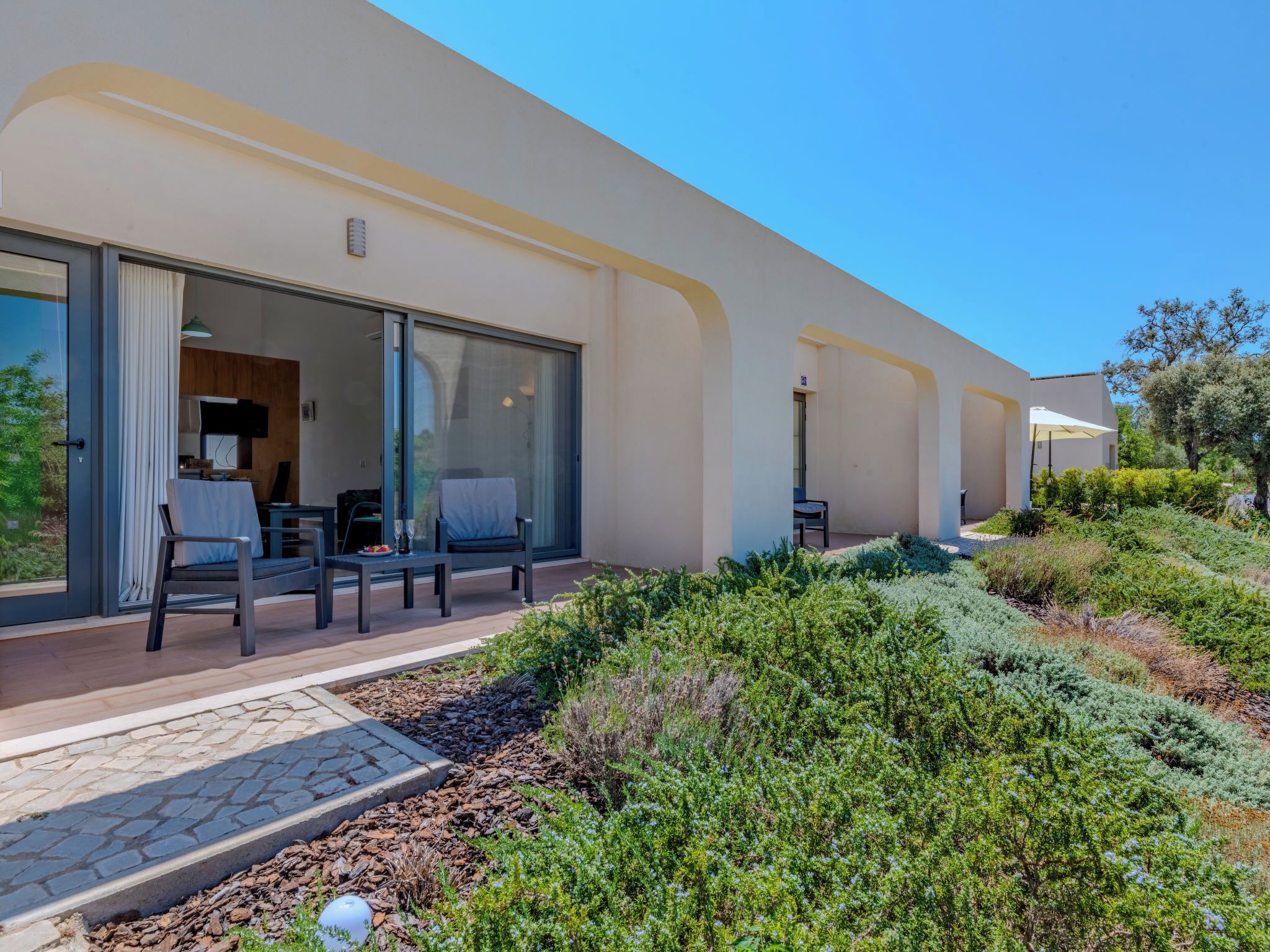 A modern building with large sliding glass doors leading to a patio area with outdoor seating.