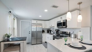 A modern kitchen with white cabinetry, stainless steel appliances, and pendant lighting. - Calm Sea Cottage: New Renovation, Modern 2BR (Bradenton)