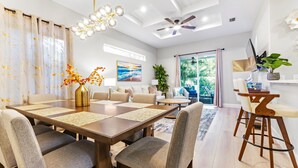 A modern dining area with a wooden table, cushioned chairs, and a ceiling fan. - Luna Nueva: Private Pool, New Renovation, Sleeps 8 (Sarasota)