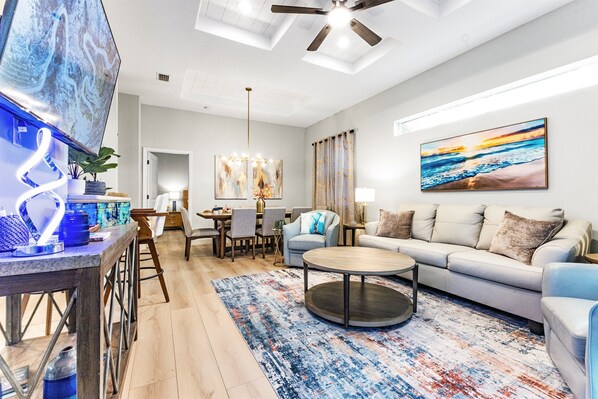 A modern living room with a sofa, coffee table, and a dining area with chairs and a table. - Luna Nueva: Private Pool, New Renovation, Sleeps 8 (Sarasota)