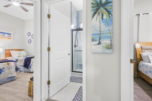 A room with two beds, a shower, and a painting of a beach scene. - Luna Nueva: Private Pool, New Renovation, Sleeps 8 (Sarasota)