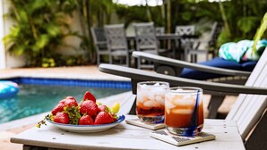 A poolside setting with a table holding a plate of strawberries and two glasses of iced drinks. - Luna Nueva: Private Pool, New Renovation, Sleeps 8 (Sarasota)