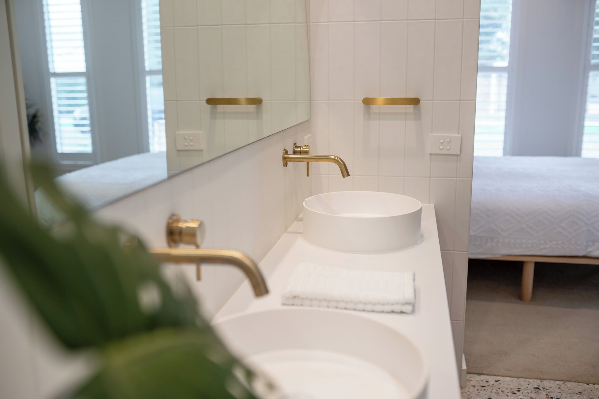 Un baño moderno con un lavamanos blanco, detalles dorados y un espejo grande.