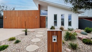 A modern house with a wooden exterior, a white front facade, and a driveway with stepping stones. - Large Retreat with Outdoor Living & Kids’ Paradise (Ocean Grove)