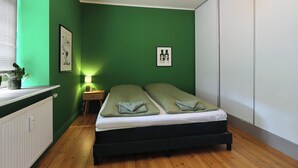 A room with a bed, a bedside table, a lamp, and a picture on the wall. - Greenbrook Suites (Aalborg)