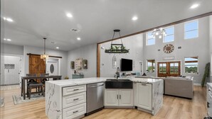 Une cuisine spacieuse avec des meubles blancs, un îlot central et un coin repas comprenant une table et des chaises en bois.