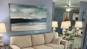 A living room with a beige sofa, a coffee table, and a painting on the wall.