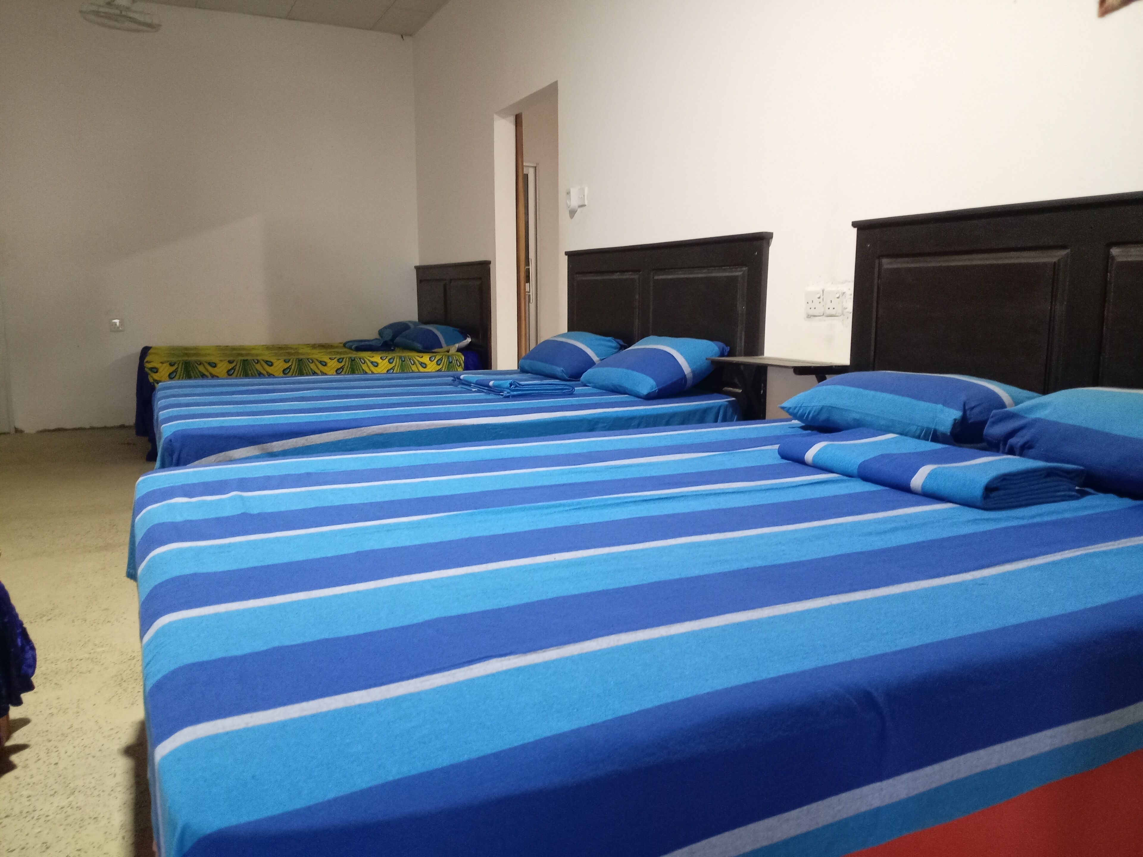 Una camera d'albergo con due letti, entrambi con lenzuola a righe bianche e blu.