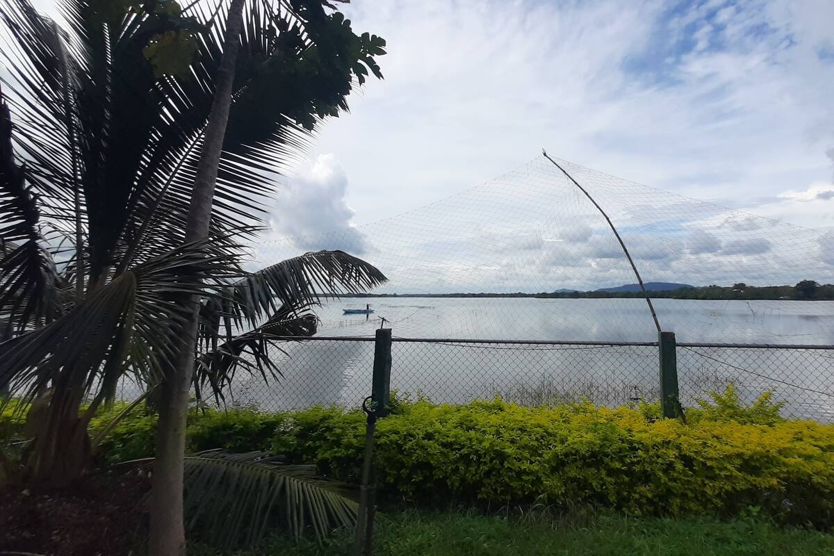 A fenced area with a body of water, a boat, and a mountainous landscape in the distance.