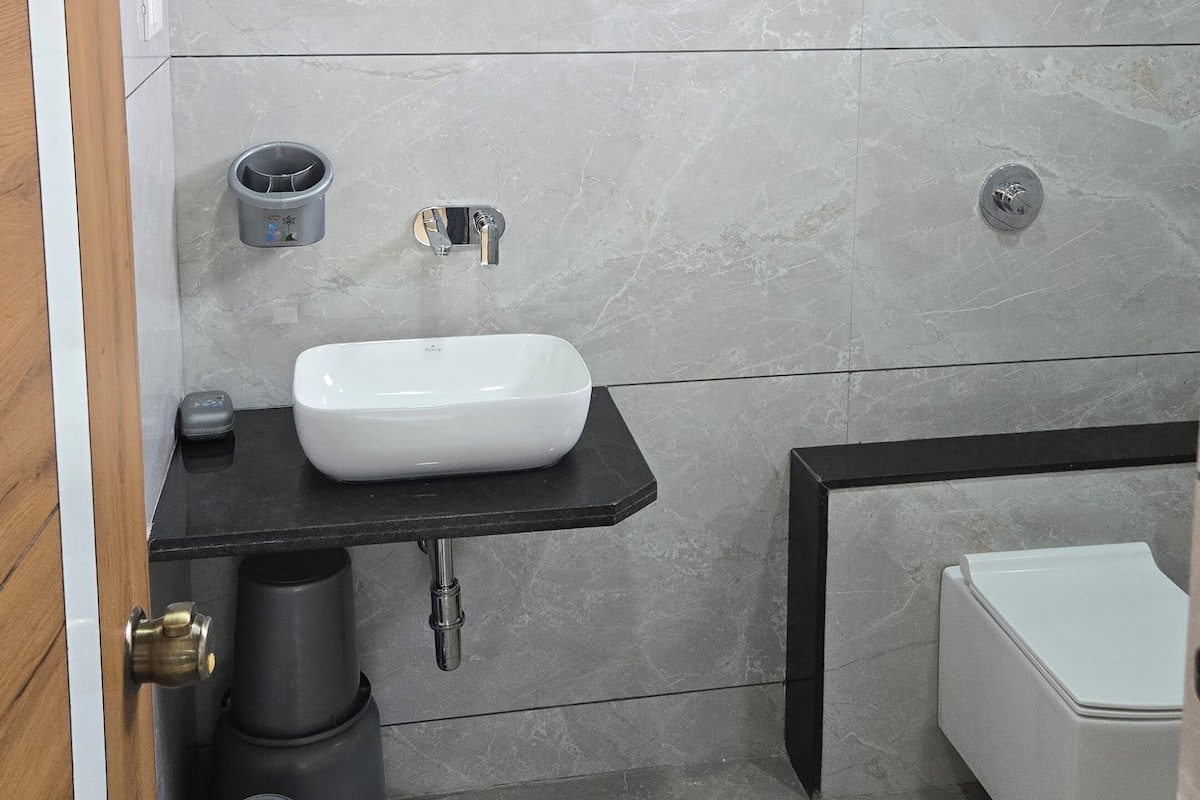 A modern bathroom with a white sink, black countertop, and a white toilet.