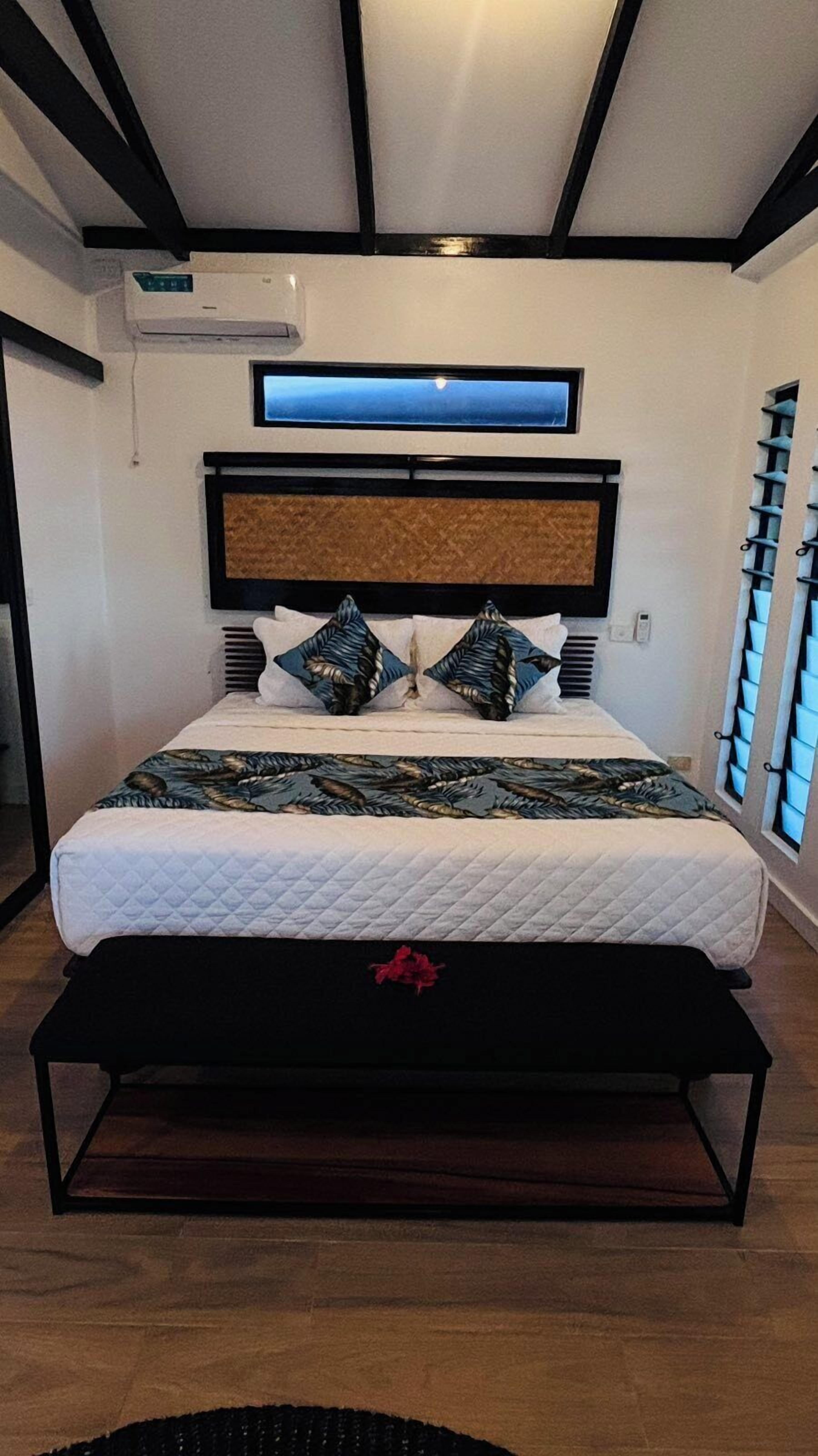 Een moderne slaapkamer met een groot bed, een hoofdbord met ingebouwde verlichting en een raam met zonwering.