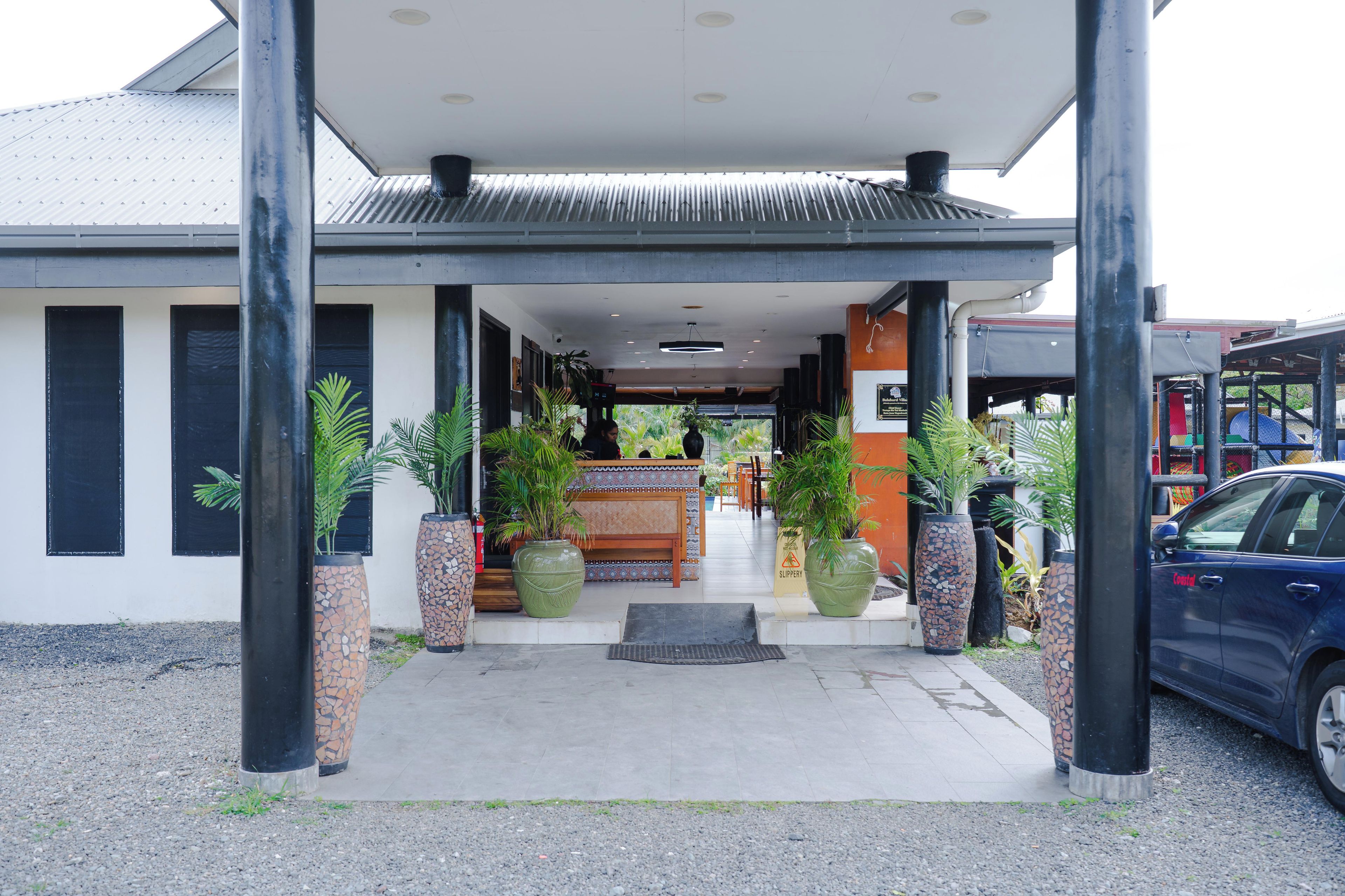 A building with a covered entrance, large potted plants, and a reception desk.