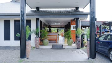 A building with a covered entrance, large potted plants, and a reception desk.