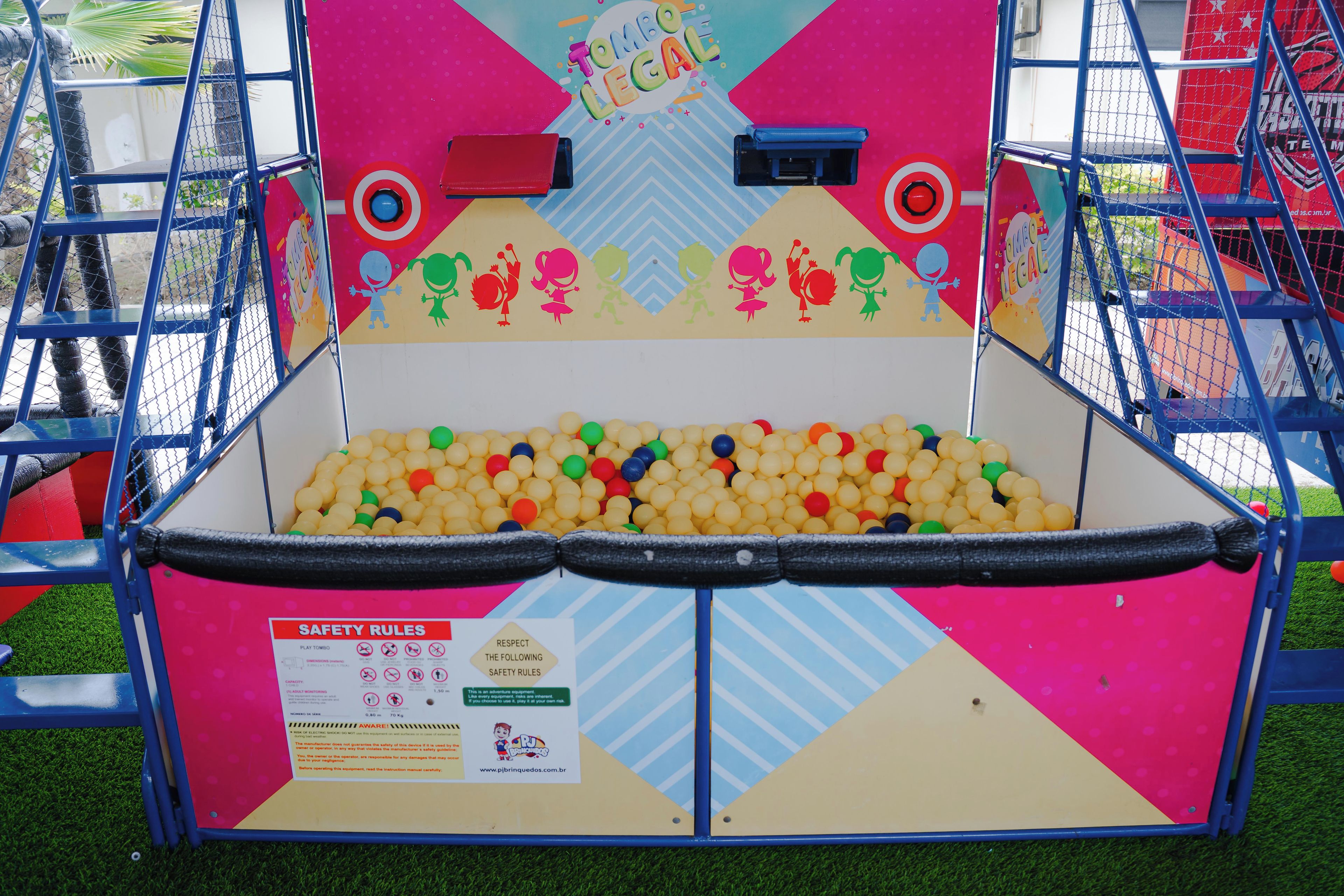 Um trampolim com regras de segurança coloridas e uma piscina de bolinhas cheia de bolas multicoloridas.