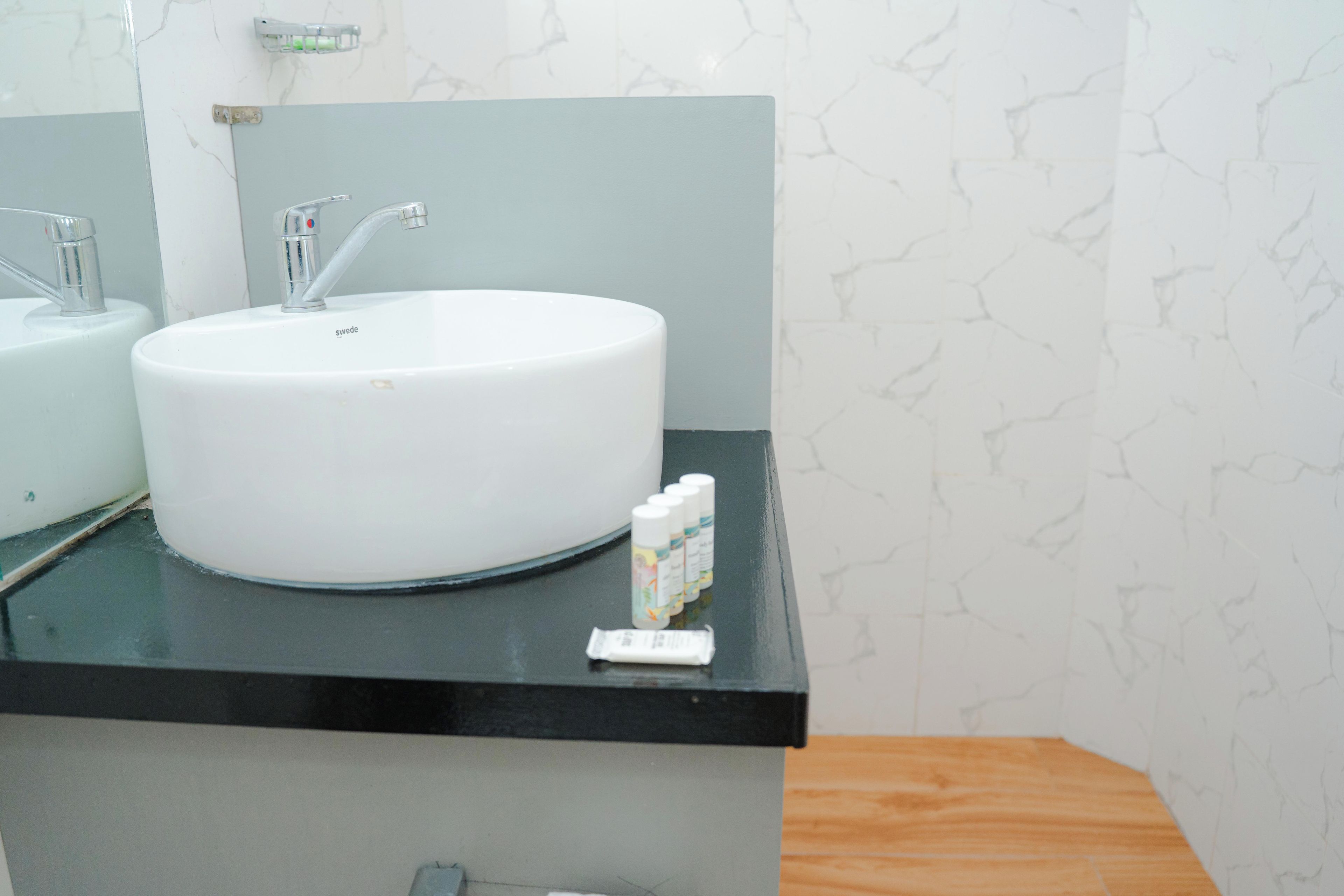 A bathroom with a white sink, a mirror, and a black countertop.
