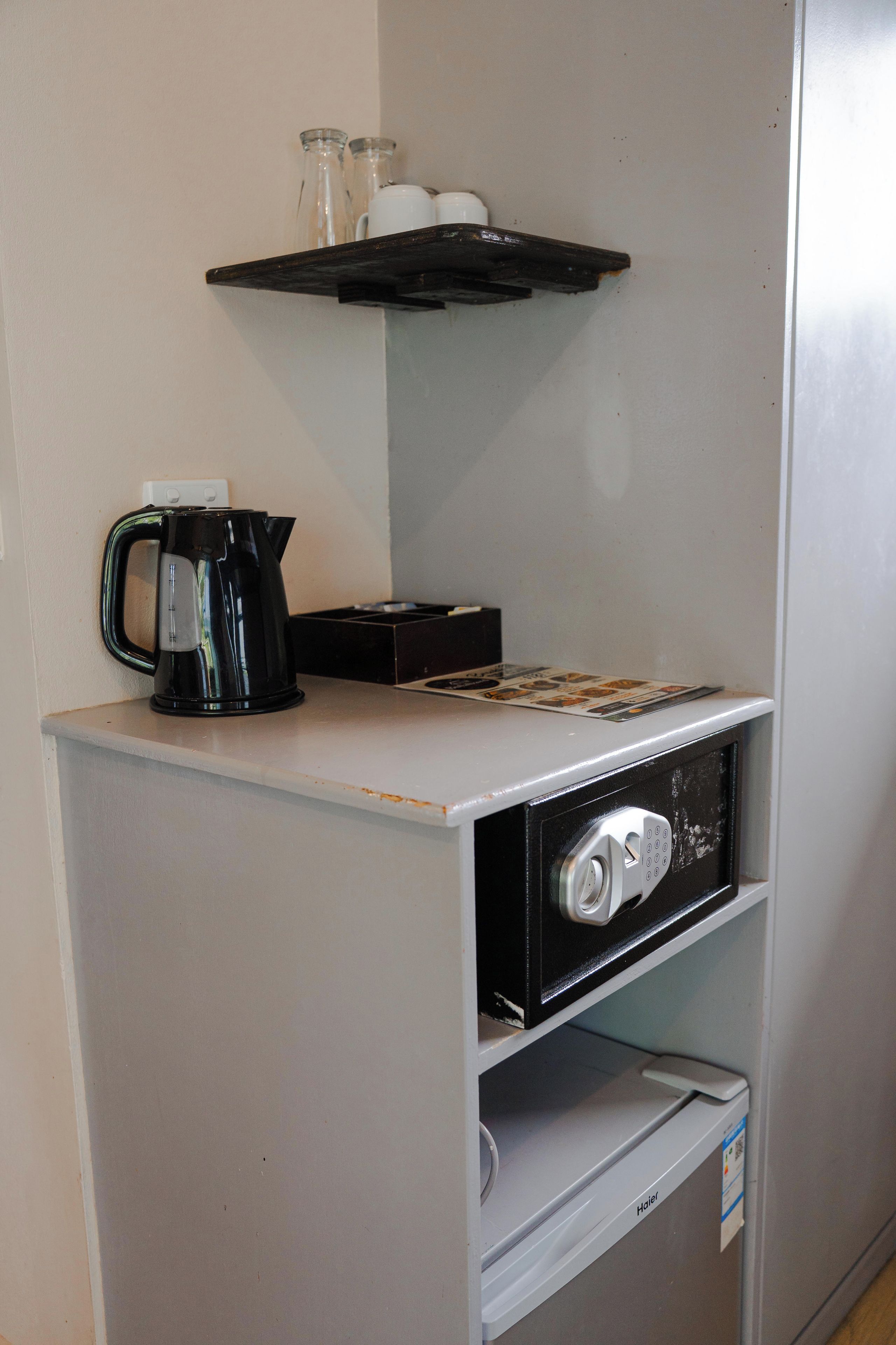Eine Küchenzeile mit Kaffeemaschine, Mikrowelle und einer kleinen Ablage für Tassen.