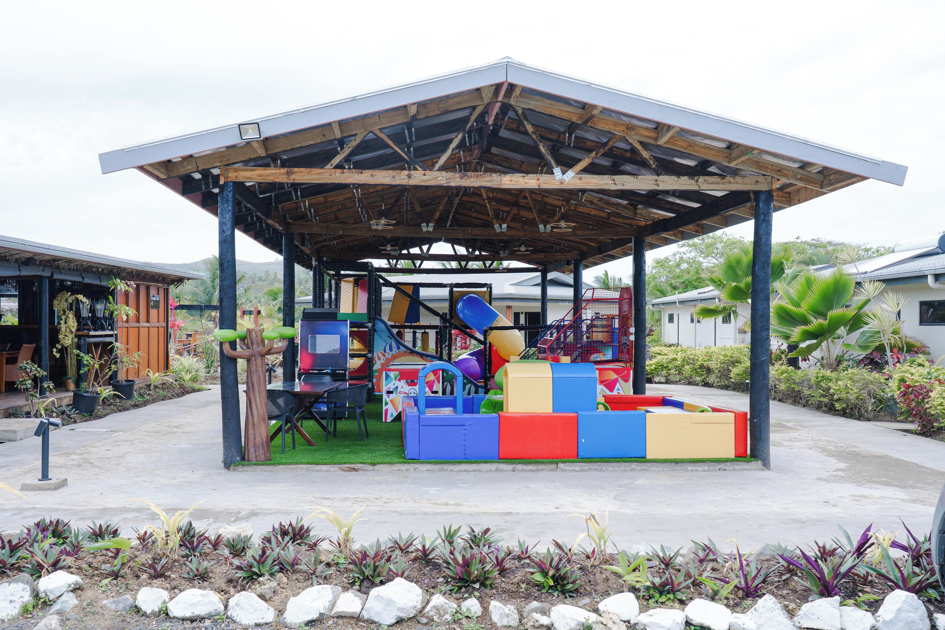 Un espace de jeux couvert avec des structures colorées et un coin salon équipé de chaises.