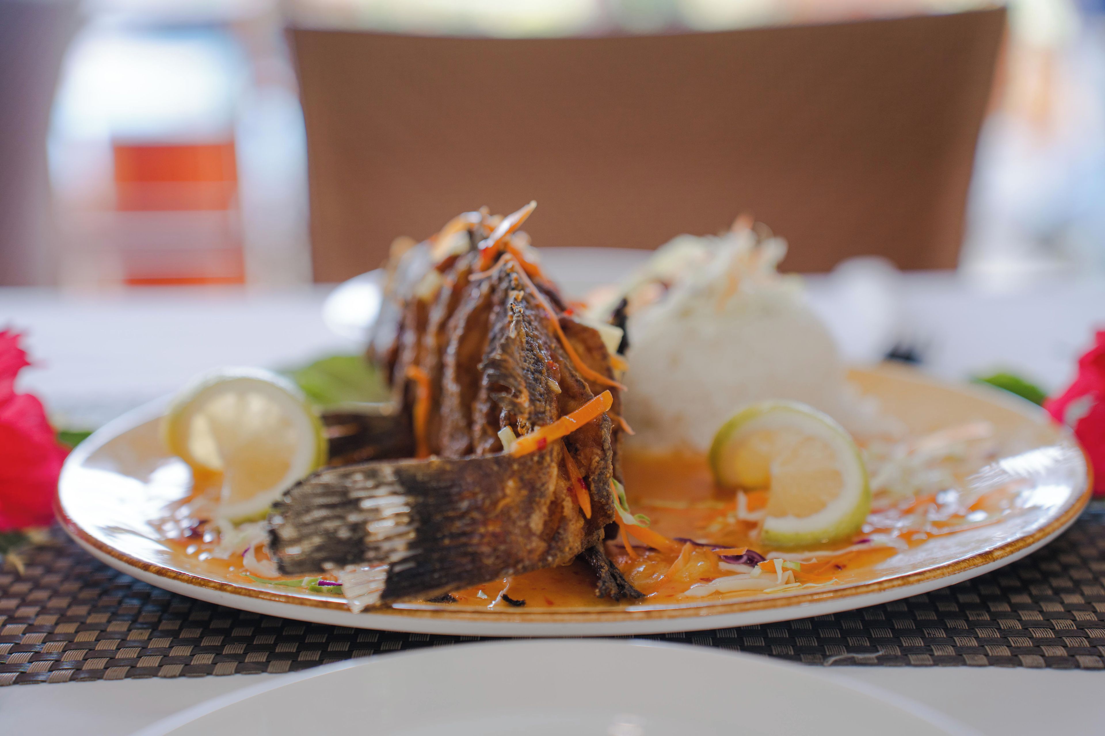 A plate with a whole fish, a mound of rice, and some vegetables.