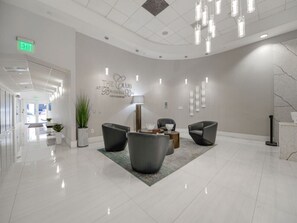 A modern lobby with a curved ceiling, a reception desk, and several seating areas with contemporary chairs and a coffee table.