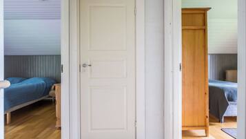 A room with a white door, two beds with blue bedding, and a wooden wardrobe.