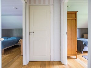 A room with a white door, two beds with blue bedding, and a wooden wardrobe.