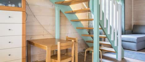 A wooden interior with a staircase, a desk, and a sofa.