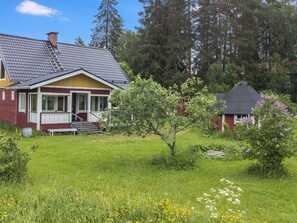 A two-story house with a sloped roof, a visible chimney, and a front porch with steps leading to the entrance.