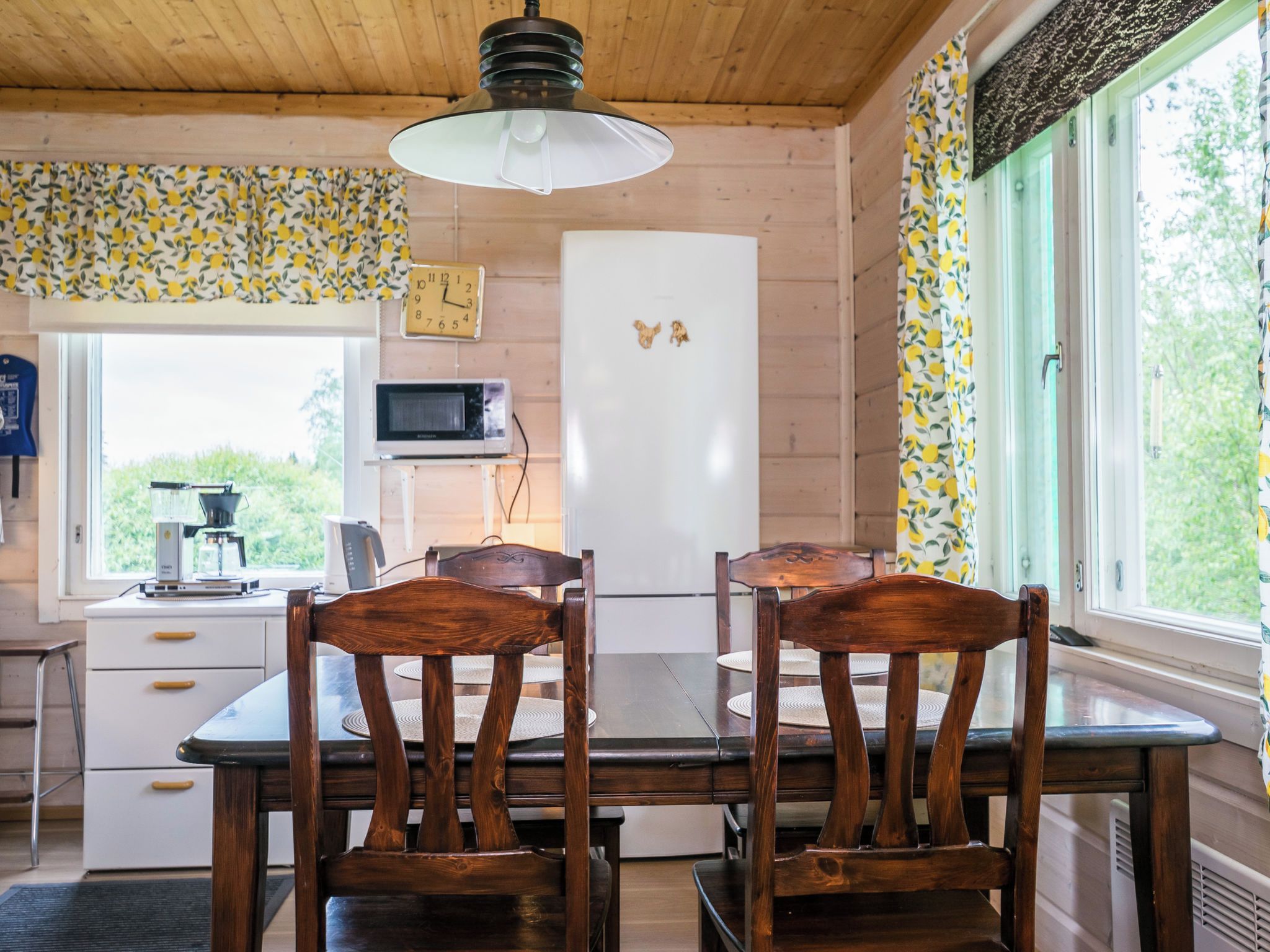 A kitchen with wooden cabinets, a white refrigerator, a microwave, and a dining table with chairs.