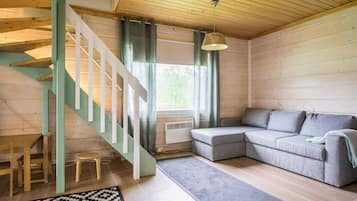 Un interno in legno con una scala, un divano grigio e un tappeto decorato.