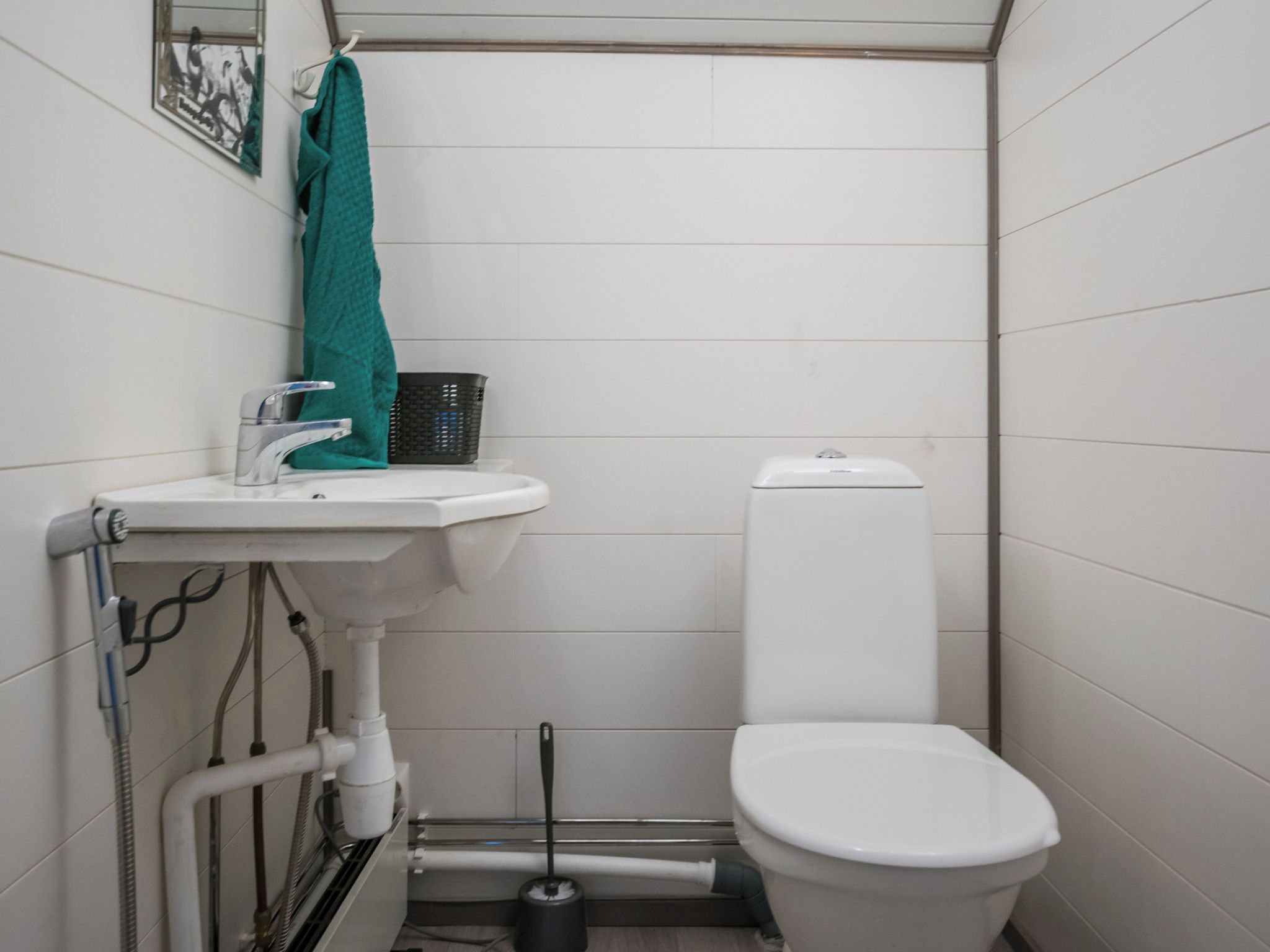 Une petite salle de bain avec un lavabo blanc, des toilettes et une serviette suspendue à un porte-serviettes.