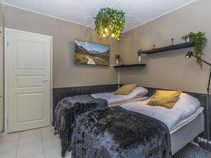A bedroom with a bed, a door, a wall-mounted TV, and a hanging plant. - Levin mini by Interhome (Kittilä)