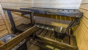 Une cuisine de taille réduite, avec des étagères en bois, un évier en métal et une poubelle.