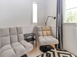 A room with two sofas, a small table, a floor lamp, and a patterned rug.