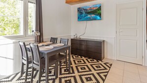 A dining area with a table, chairs, a patterned rug, a fireplace, and a TV on the wall. - Levin lumi by Interhome (Kittilä)