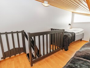 A room with a wooden staircase, a bed with a white mattress, and a window with a view.