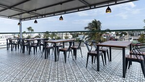 Un espace extérieur aménagé avec des tables et des chaises, un sol à motifs et des lampes suspendues.