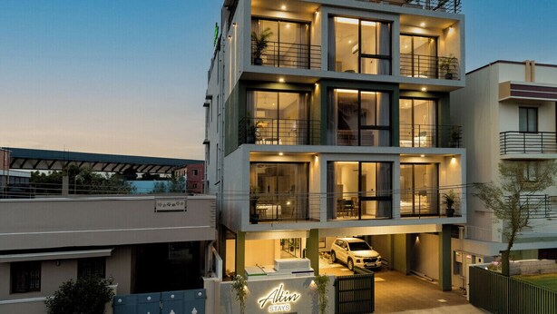 Un hôtel moderne à deux étages, doté de balcons, de grandes fenêtres et d’une voiture garée dans l’allée.