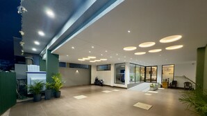 Un hall d’entrée spacieux au design moderne, comprenant un comptoir d’accueil, un espace salon et un escalier menant aux étages supérieurs.