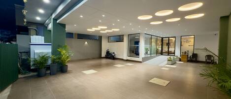 A spacious lobby with a modern design, featuring a reception desk, seating area, and a staircase leading to upper floors.
