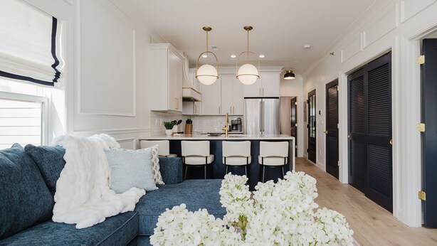 A modern kitchen with white cabinets, a central island, and pendant lighting.