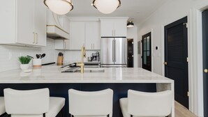 A modern kitchen with white cabinets, stainless steel appliances, and a central island with bar stools.