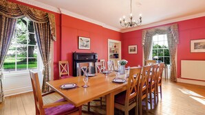 A dining room with a wooden table set for six, surrounded by wooden chairs with cushioned seats.
