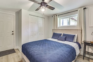A bedroom with a bed, a ceiling fan, a window with curtains, and a door. - Withlacoochee River Retreat w/ Dock: Paddle & Fish (Dunnellon)
