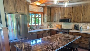 Una cocina con armarios de madera, un refrigerador de acero inoxidable, una encimera de granito y un horno empotrado.